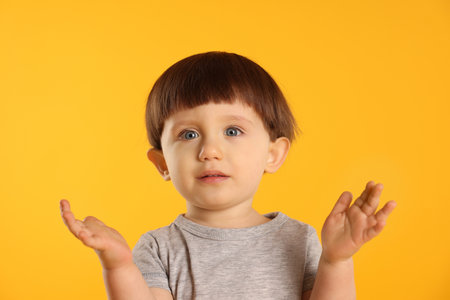 Portrait of cute little boy on yellow backgroundの写真素材