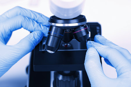 Scientist examining sample on slide under microscope, closeup