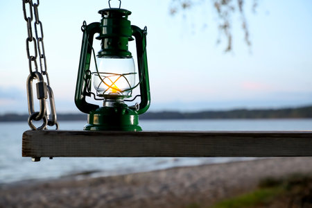 Vintage kerosene lamp on swing at beach in eveningの写真素材