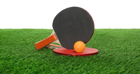 Ping pong rackets and ball on green grass against white background. Sport equipmentの写真素材