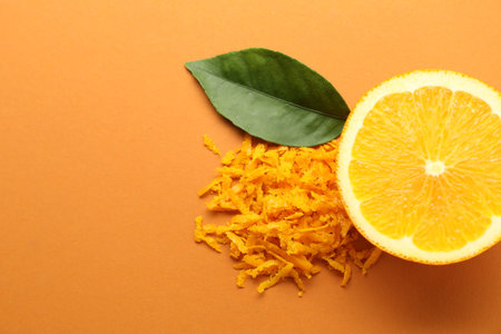 Pile of fresh orange zest, cut fruit and leaf on color background, flat lay. Space for textの写真素材