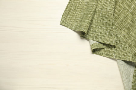 Green tablecloth on white wooden background, top view. Space for textの写真素材
