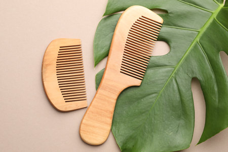 Wooden combs and monstera leaf on beige background, flat layの写真素材