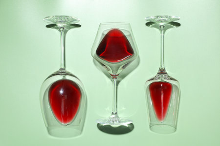 Glasses of red wine on light green background, flat lay