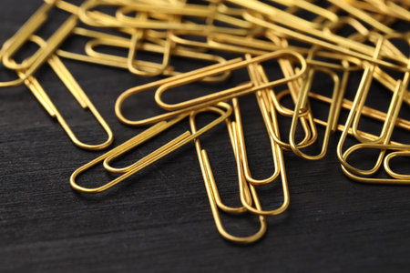 Many golden paper clips on black table, closeupの写真素材