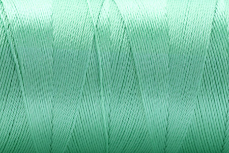 Beautiful light green sewing thread as background, closeup