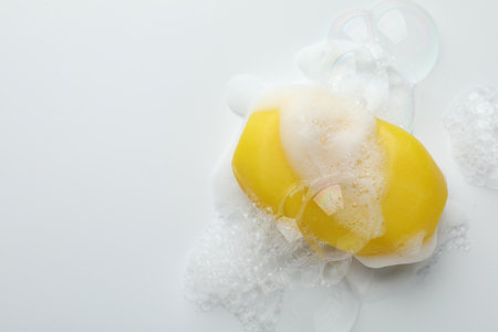 Soap bar with foam on white background, top view. Space for text