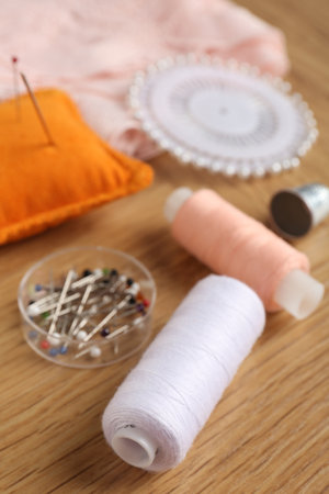 Sewing threads and pins on wooden table, closeup