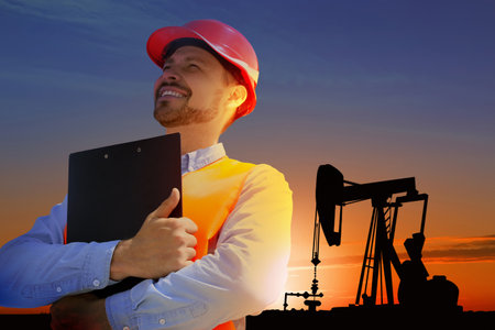 Worker at oil production site with crude oil pumpの写真素材