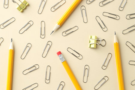 Paper clips and pencils on beige background, flat layの写真素材