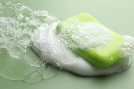 Soap bar with foam on green background, closeupの写真素材