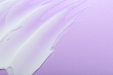 Cream sample on violet background, top view. Space for text