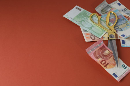 Euro banknotes and scissors on brown background, space for textの写真素材