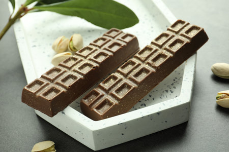 Tasty chocolate with pistachios and knafeh on grey textured table, closeup