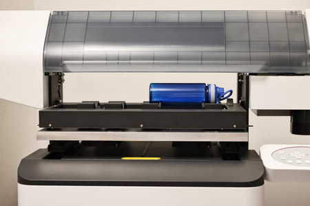 Modern printer and empty bottle indoors, closeup