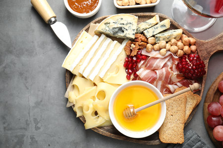 Different types of cut cheese and other snacks served with wine on gray textured table, flat lay. Space for textの写真素材