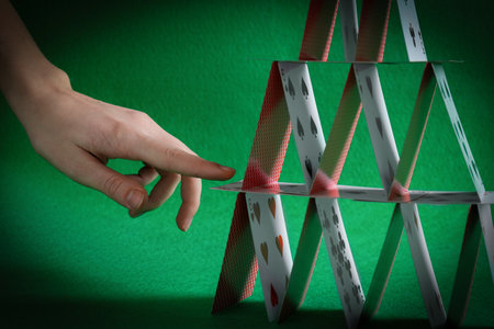 Woman destroying house of playing cards on green background, closeup
