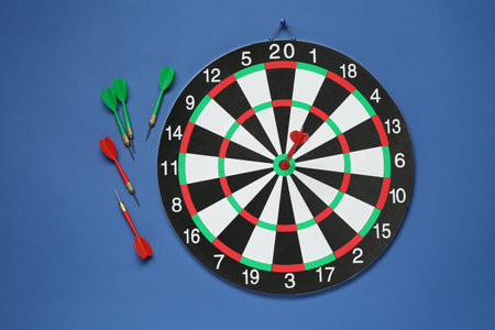 Dart board and colorful arrows on blue background, flat layの写真素材