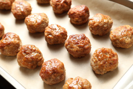 Many delicious meatballs on parchment in baking dish, closeupの写真素材