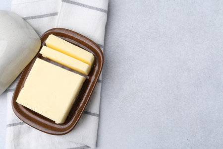 Cut butter in dish on light grey table, top view. Space for textの写真素材