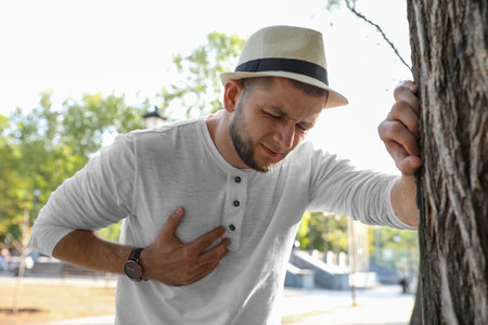 Man having heart attack near tree in park