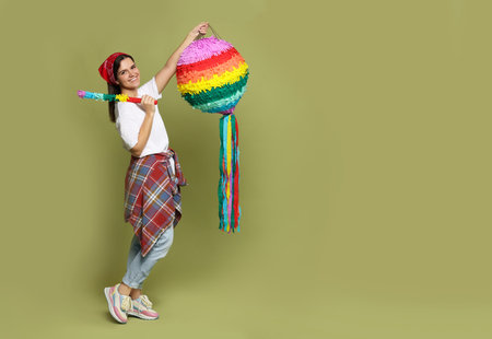 Happy woman with colorful pinata and stick on green background, space for textの写真素材