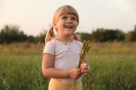 Cute little girl with plants at meadow. Child enjoying beautiful natureの写真素材
