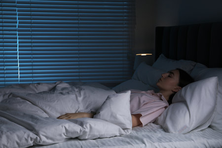 Young woman sleeping in soft bed at nightの写真素材