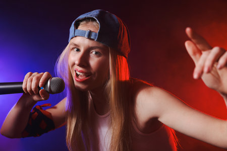 Talented singer performing on dark background with color lightsの写真素材