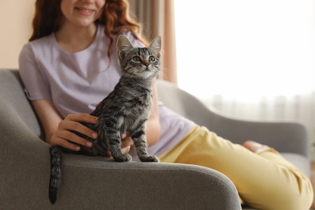 Teenage girl with cute cat on sofa at home, closeupの写真素材