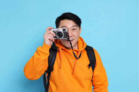 Traveller taking photo on light blue backgroundの写真素材