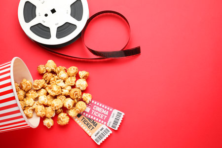Sweet popcorn, movie tickets and film reel on red background, flat layの写真素材