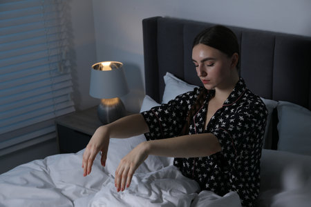 Young woman suffering from sleepwalking on bed at homeの写真素材