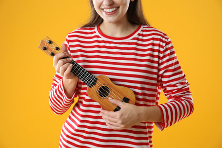 Woman playing ukulele on orange background, closeupの写真素材