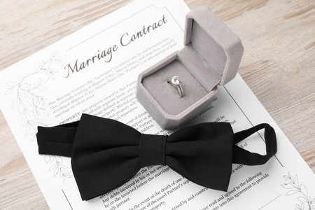 Marriage contract, bowtie and ring on light wooden table, above viewの写真素材