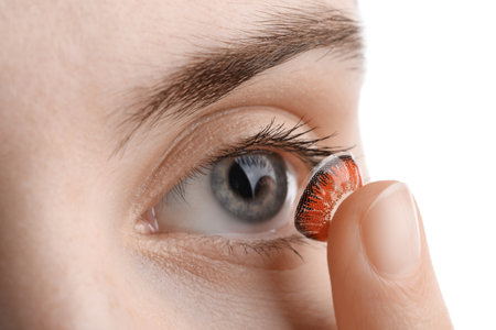 Woman putting in red color contact lens on white background, closeupの写真素材
