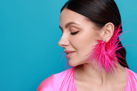 Beautiful young woman wearing stylish earrings on light blue background, closeup. Space for textの写真素材