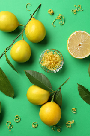 Lemon zest, fresh fruits and leaves on green background, flat layの写真素材