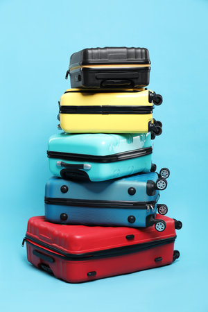 Stack of colorful suitcases on light blue background