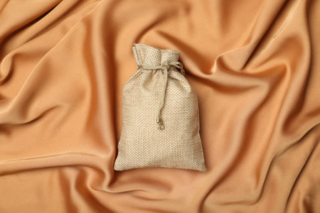 Beige burlap sack on orange fabric, top viewの写真素材