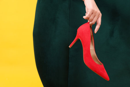 Woman holding red high-heeled shoe on color background, closeupの写真素材