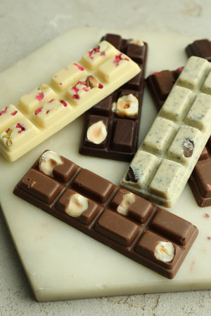 Delicious chocolate bars with different flavors on light table, closeup