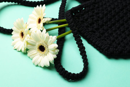 Macrame shopping bag with beautiful flowers on turquoise background, closeupの写真素材