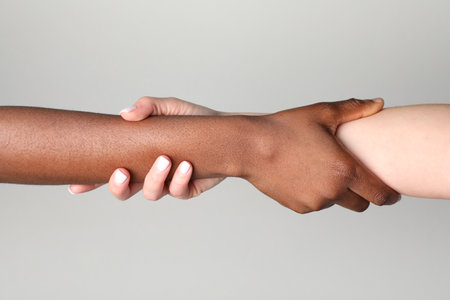 Stop racism. People of different skin colors holding hands on light gray background, closeupの写真素材