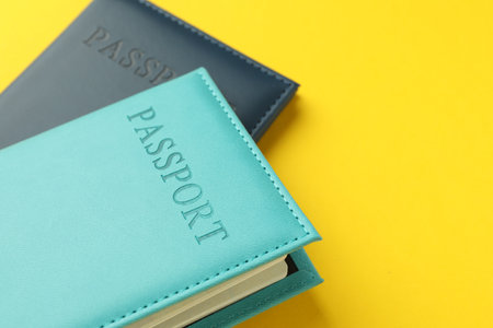 Passports in color covers on yellow background, closeup. Space for textの写真素材