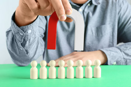 Man with magnet attracting game pieces at green table, closeupの写真素材