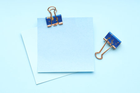 Binder clips and notes on light blue background, flat lay. Space for textの写真素材
