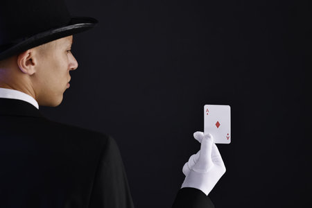 Illusionist with playing card on black backgroundの写真素材