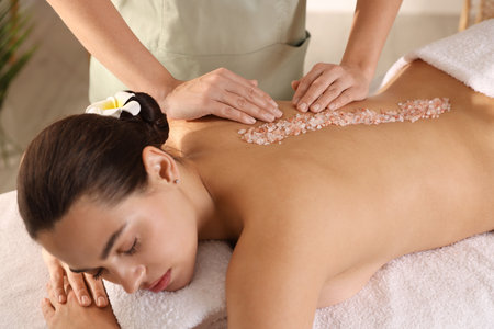 Woman receiving massage with sea salt in spa salonの写真素材