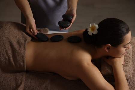 Woman receiving hot stone massage in spa salonの写真素材